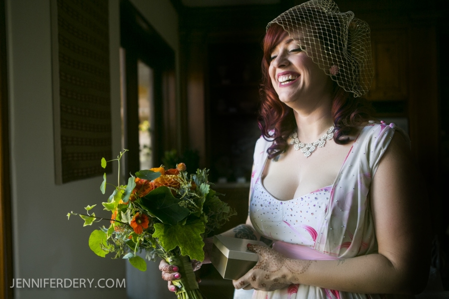 photo of bride with red hair, vintage dress and geranium + nasturtium wedding bouquet