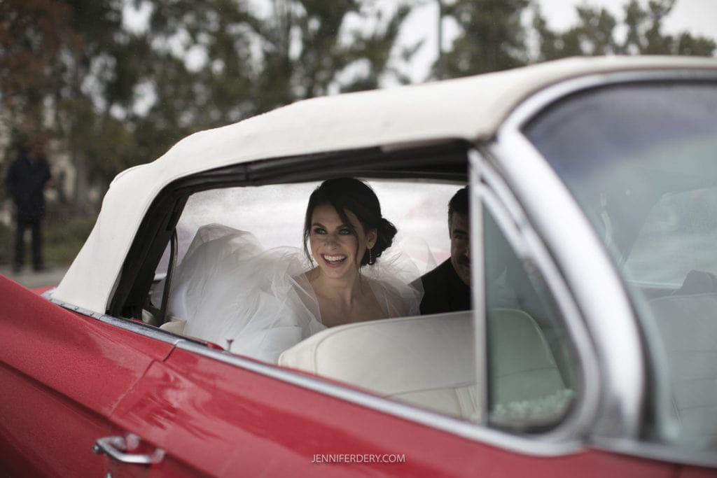 bride arriving in a red vintage convertible to her wedding at founders chapel