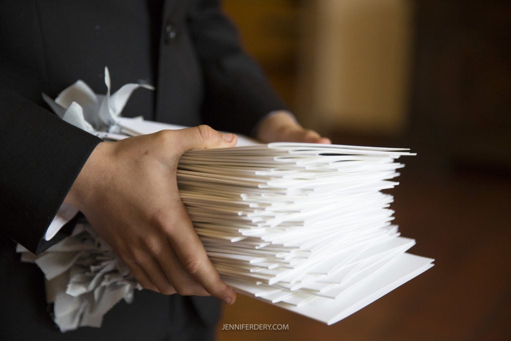 close up photo of a ring bearer holding a stack of wedding ceremony programs