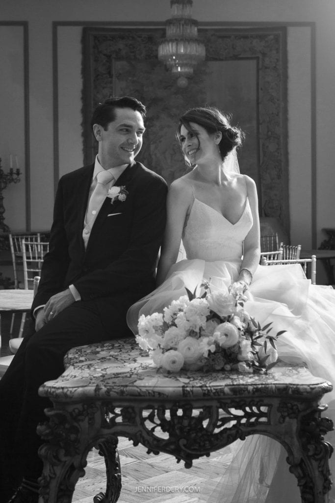 b&w photo of a bride and groom sitting on a table together inside founder's chapel after their wedding