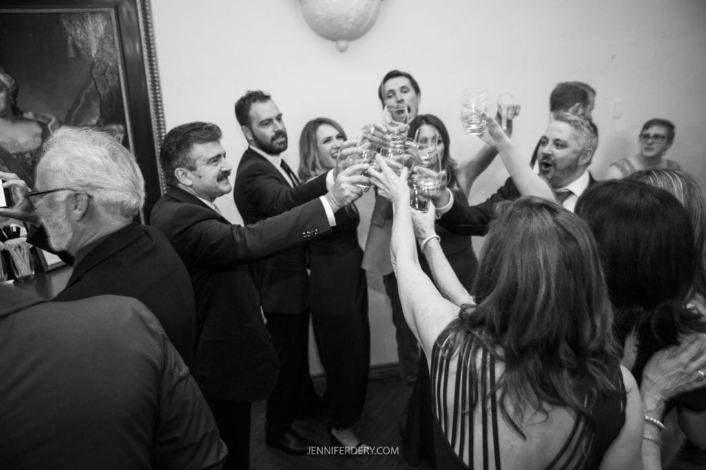 black and white candid photo of a group of friend toasting at a wedding reception