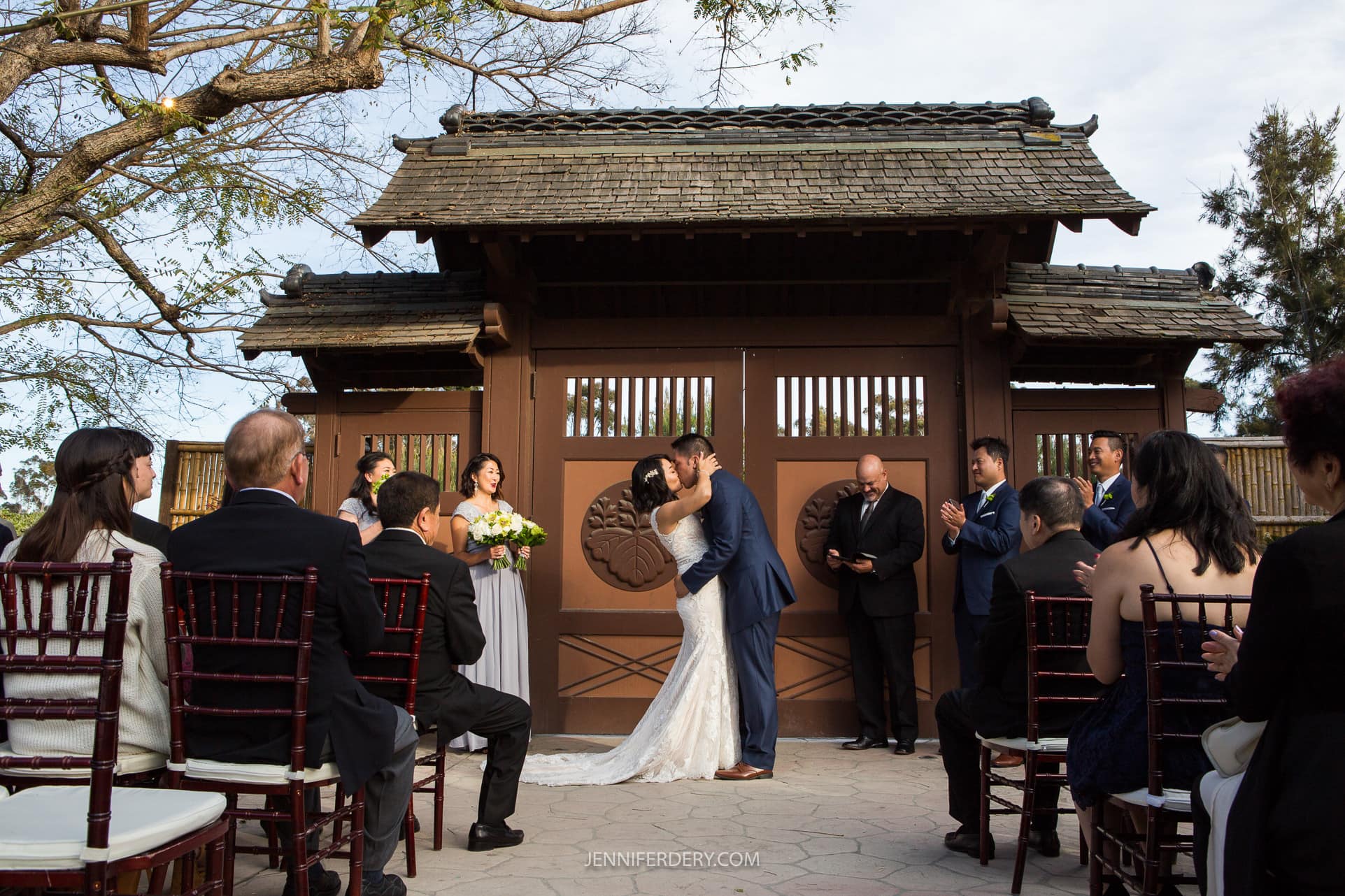 wedding couple at japanese garden balboa park showing their first kiss after the wedding ceremony in front of the ceremonial doors to the garden