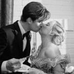 balck and white photo of a couple kissing after cutting their wedding cake