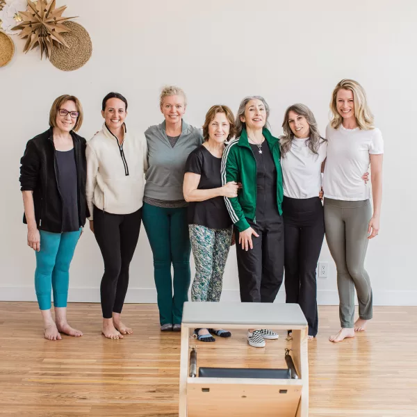 photo of nicole martin and her students at a ritual pilates workshop and branding photo session. group of seven women wearing various types of workout attire.