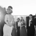 black and white photo of a wedding couple during their first dance with bridal party in the background. shown on croquet lawn at rancho valencia hotel