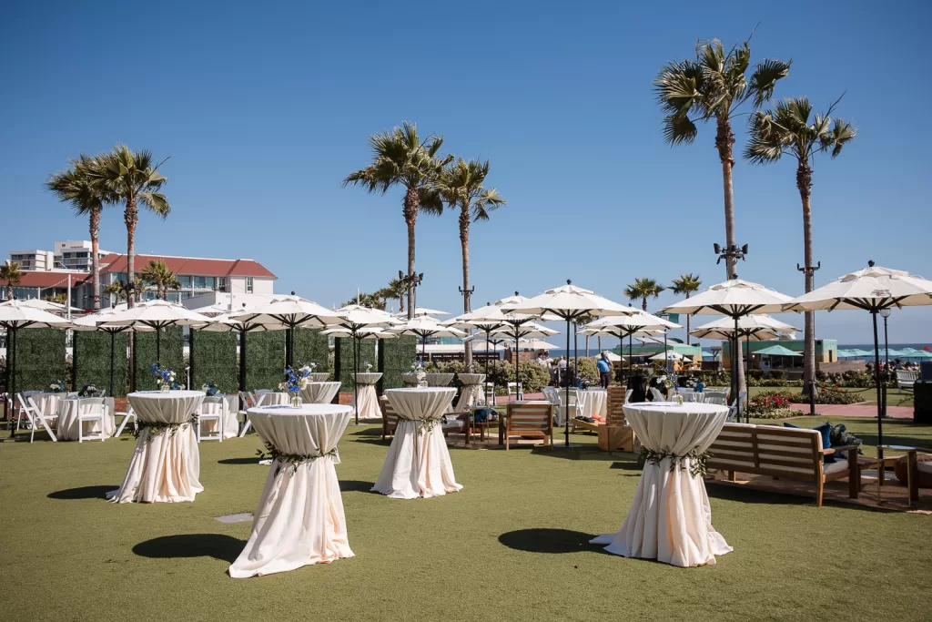 photo of a cocktail reception set up with white market umbrellas on the main lawn at the hotel del coronado