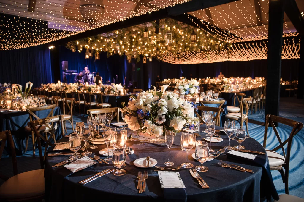 white floral arrangements, fairy lights, candles, and navy draped ballroom of southpointe ballroom at the hotel del coronado, CA